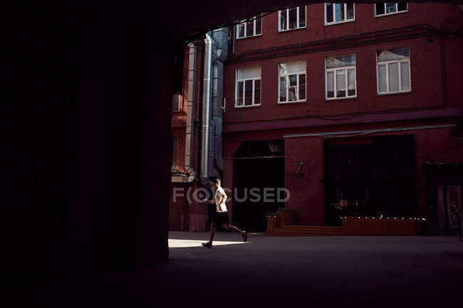 Вид сбоку на неузнаваемого бегуна-мужчину, прыгающего на улице во время тренировки в городе летом — стоковое фото