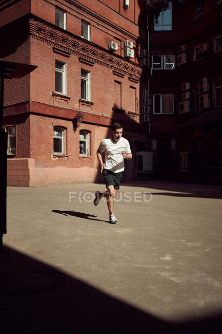 Мужчина бегает по улице во время тренировок в городе летом — стоковое фото