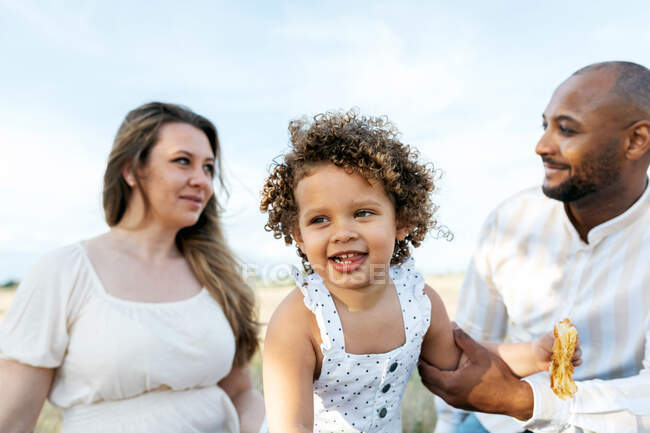 Glückliche multiethnische Familie mit süßer kleiner Tochter genießt sommerliches Picknick in der Natur — Stockfoto