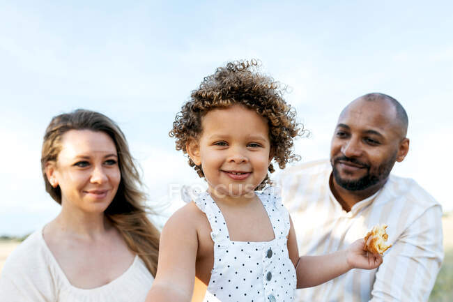 Familia multiétnica feliz con linda hija disfrutando de un picnic de verano en la naturaleza - foto de stock