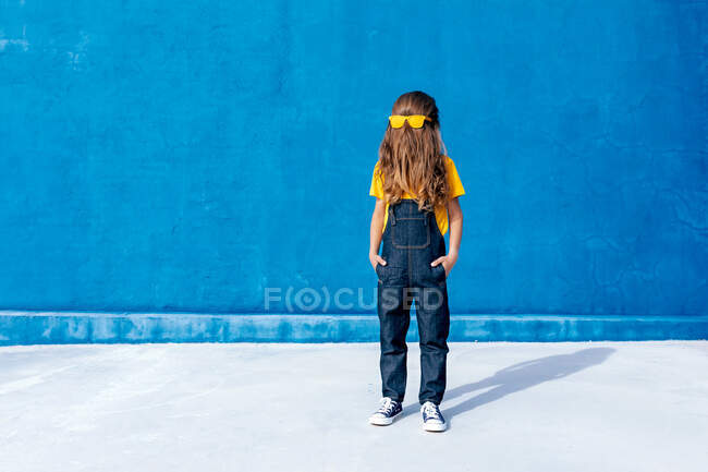 Anonymer cooler Teenager mit gelber Sonnenbrille auf langem Haar, das Gesicht auf blauem Hintergrund verdeckt — Stockfoto