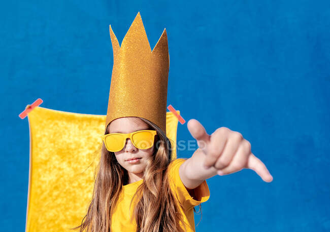 Cool teen hipster in golden king crown and sunglasses showing shaka sign while looking at camera on two colored background — Stock Photo