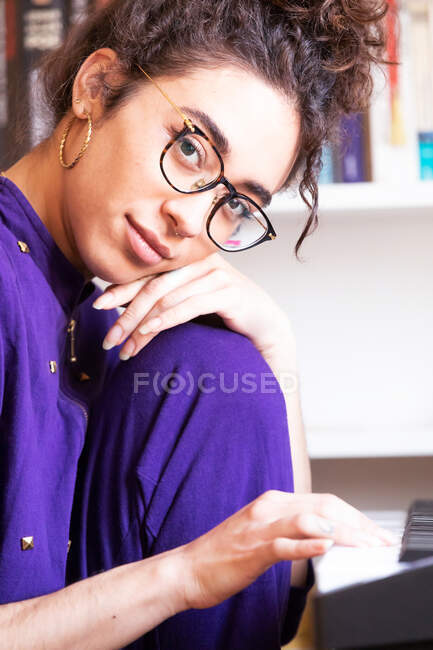 Side view of young Hispanic female playing electric piano while practicing music skills at home — Stock Photo