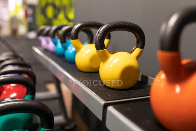 Conjunto de kettlebells coloridos de vários pesos colocados em fila no moderno centro de fitness — Fotografia de Stock