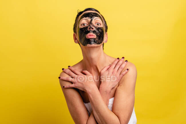 Середньолітня самиця з чорною шкірою від маски і пухирцями, дивлячись на камеру з перехрещеними руками — стокове фото