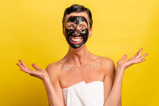Весела жінка середнього віку з чорною шкірою від маски стоїть на жовтому студійному фоні, дивлячись на камеру — стокове фото