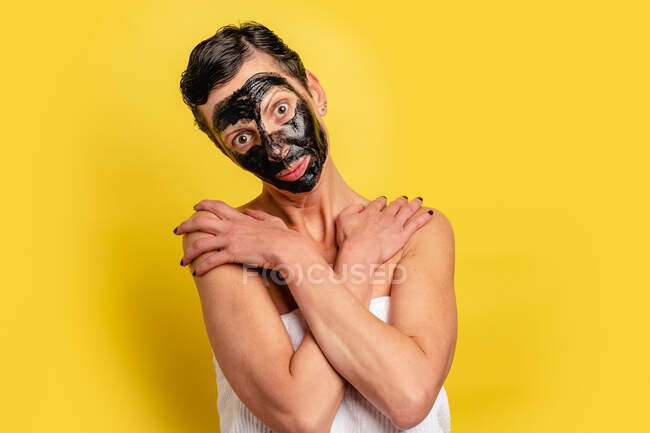 Середньолітня самиця з чорною шкірою від маски стоїть на жовтому фоні студії дивлячись на камеру з перехрещеними руками — стокове фото
