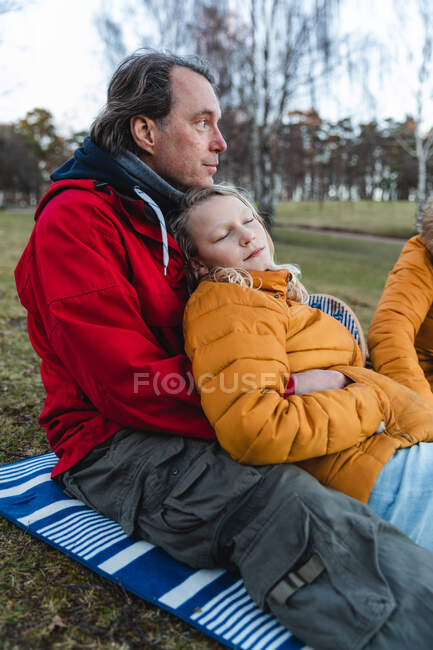 Любимая семья с дочкой-подростком отдыхает на деревянной набережной и наслаждается пикником в осеннем лесу — стоковое фото