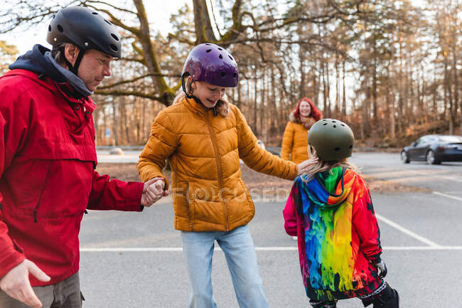 Père tenant la main de la fille adolescente à cheval skateboard dans le parc d'automne pendant le week-end — Photo de stock