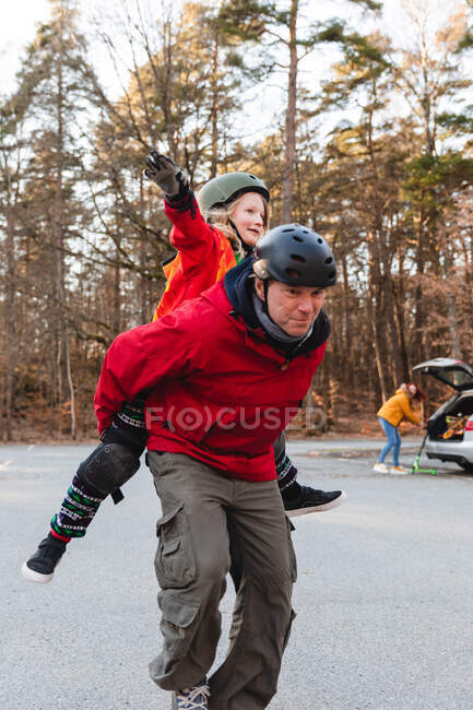 Content father piggybacking carefree child while having fun together in park in autumn — Stock Photo