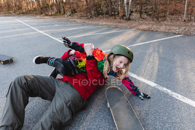 Anónimo padre cosquillas chica positiva tumbado en el suelo en el parque de otoño y divertirse - foto de stock