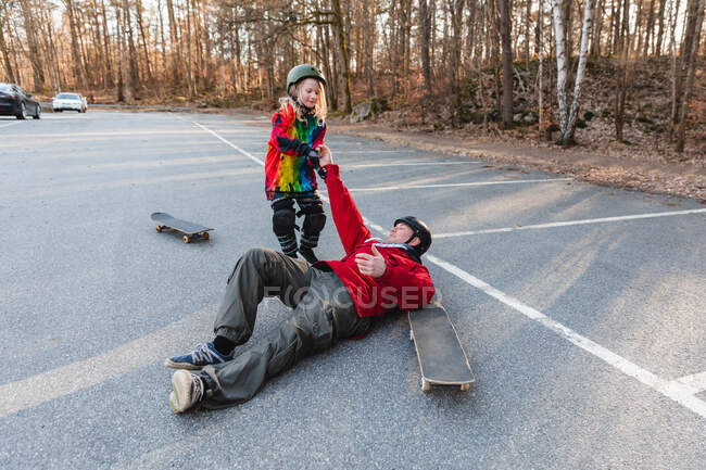 Зверху дочка допомагає батькові встати з землі — стокове фото