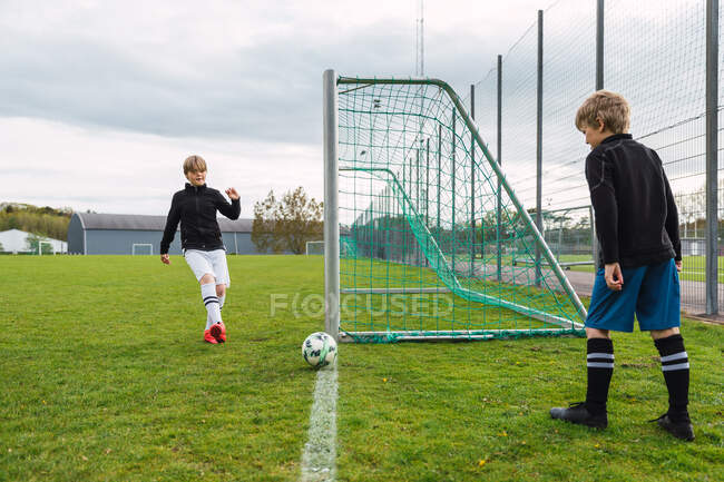 Ragazzi adolescenti in abbigliamento sportivo che giocano a calcio insieme sul campo verde in estate — Foto stock