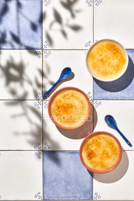 Верхний вид на вкусный десерт крем Брюле с карамельной корочкой подается в Ramekins на столе с солнечным светом — стоковое фото