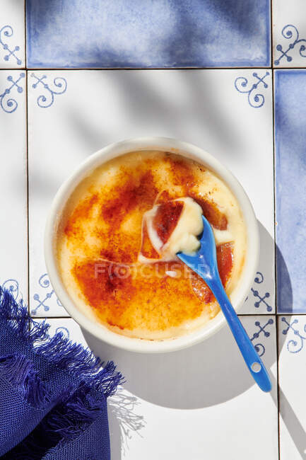 Vista superior da saborosa sobremesa creme brulee com crosta de caramelo servida em ramekin na mesa com luz solar — Fotografia de Stock