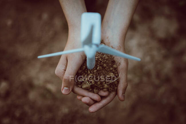 Alto angolo di coltura anonimo persona con terreno e figura del mulino a vento che rappresenta il concetto di energia alternativa per l'agricoltura — Foto stock