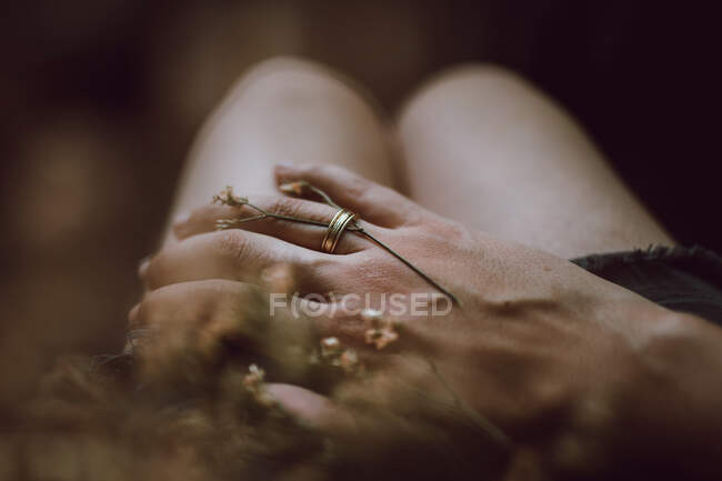 Alto ángulo de la cosecha novio anónimo con anillo y tallo de flor en el dedo la colocación de la mano en la novia - foto de stock