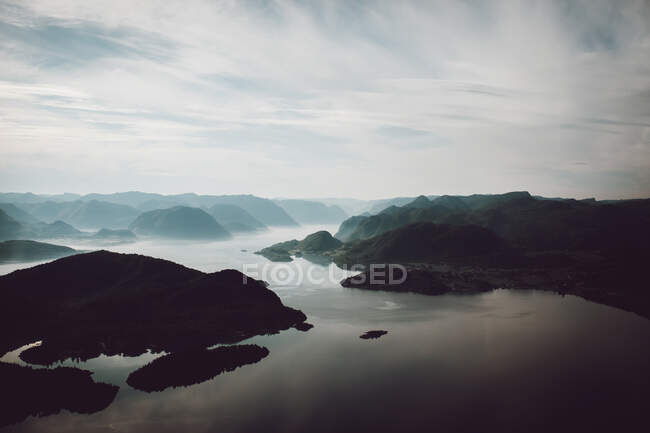 Scenic landscape with water stream flowing among hills covered with plants in gloomy cloudy day — Stock Photo