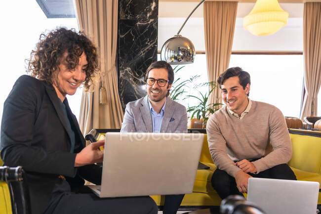 Well dressed entrepreneurs sitting in lobby of hotel and talking about business strategy while suing laptop — Stock Photo