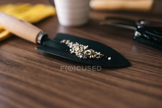 Soft focus of closeup shovel with shell gravel prepared for gardening on wooden table — Stock Photo