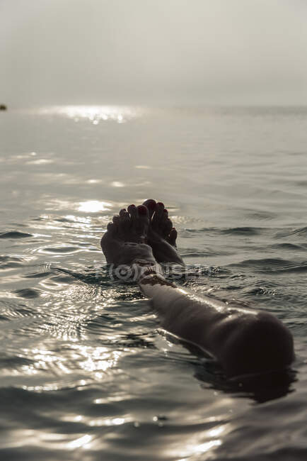 Куст босиком ноги неузнаваемой женщины, лежащей в морской воде и наслаждаясь солнечным утром во время отпуска на Плайя-де-Муро — стоковое фото