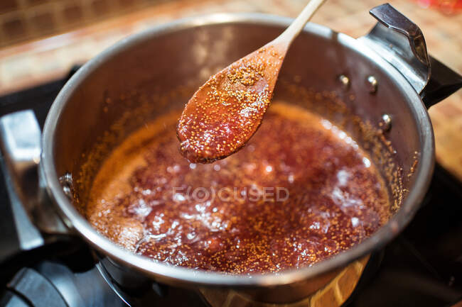 From above of crop anonymous person stirring fig confiture in cooker on stove at home — Stock Photo