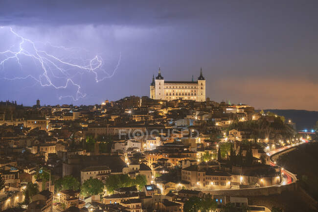 Paysage urbain avec vieux château célèbre Alcazar de Tolède placé en Espagne sous le ciel nuageux dans la nuit pendant l'orage — Photo de stock