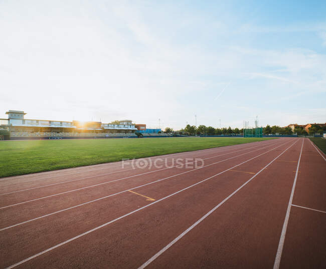 Scenic view of tracks and sports field against tribunes under shiny sky in evening town — Stock Photo