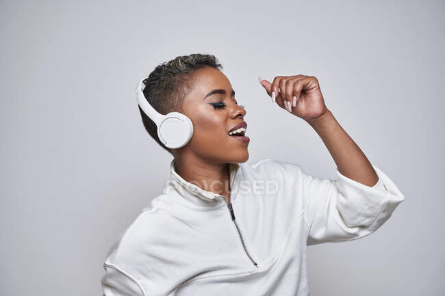 Energetic ethnic woman in wireless headphones and trendy clothes dancing hip hop with open mouth and eyes closed — Stock Photo