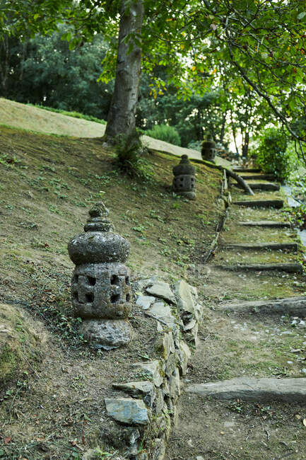Lanterne asiatique en pierre brute sur le terrain contre les escaliers et les arbustes dans le parc de Bali Indonésie — Photo de stock
