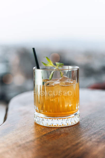 Crystal glass of whiskey cocktail with ice cubes and mint leaves on table bar — Stock Photo
