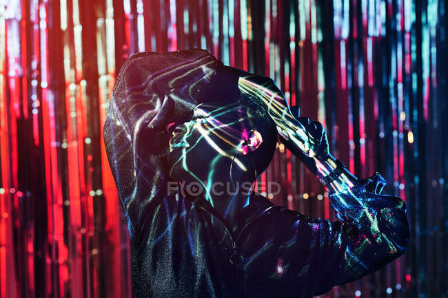 Smiling young African American female with closed eyes dancing in ultraviolet light on blurred background — Stock Photo