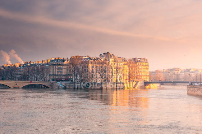 Edifícios residenciais históricos localizados na costa do rio ondulante que flui em Paris na noite de inverno — Fotografia de Stock