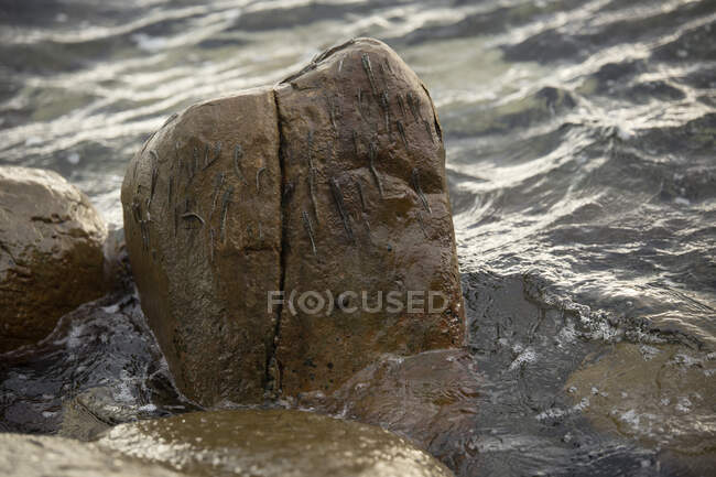 De arriba de la roca mojada resbaladiza lavada por el agua transparente del río a la luz del día - foto de stock