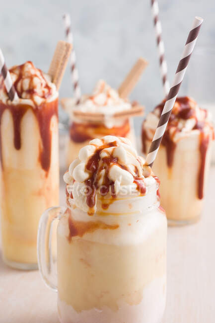 Verschiedene Gläser mit süßem Karamell-Milchshake mit Vanilleeis und Waffelplätzchen auf dem Tisch — Stockfoto