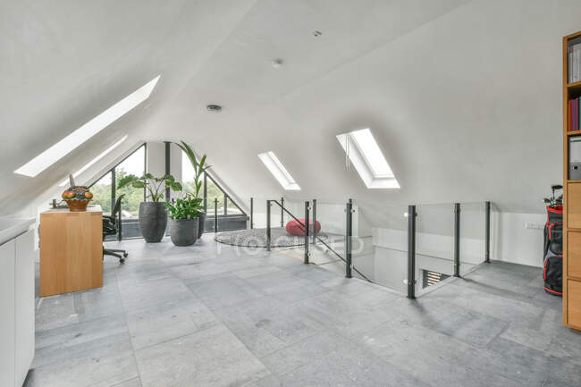 Сірий інтер'єр сучасної просторої кімнати на другому поверсі великого будинку, прикрашеного начинкою рослин біля столу і стільця. — стокове фото