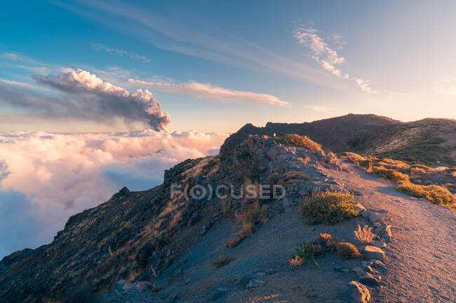 Sunrise on a high altitude mountain trail amid soft, thick white clouds and the eruption of a volcano in the background. Cumbre Vieja volcanic eruption in La Palma Canary Islands, Spain, 2021 — Stock Photo