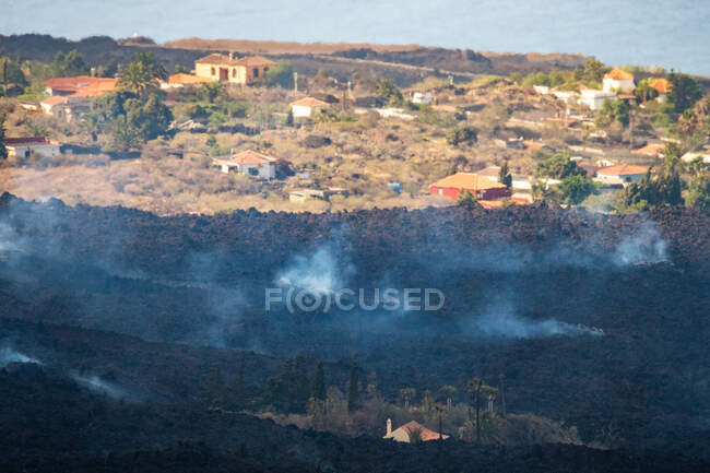 Lava caliente y magma saliendo del cráter mientras arrasan las casas de la ciudad. Cumbre Vieja erupción volcánica en La Palma Islas Canarias, España, 2021 - foto de stock