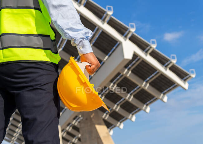 Niedriger Winkel Rückansicht der Ernte unkenntlich männlichen Inspektor in Weste mit Schutzhelm gegen moderne Solarkraftwerk — Stockfoto