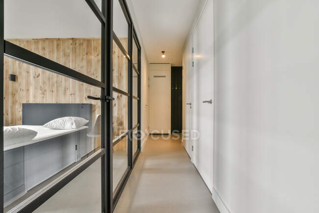 Interno di corridoio luminoso con porte di vetro di camera da letto in elegante appartamento contemporaneo — Foto stock
