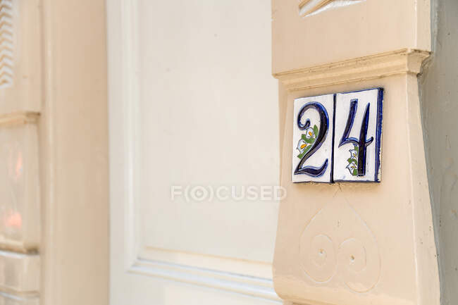 Números em sinais com folhagem e ornamento floral na parede da casa envelhecida na cidade — Fotografia de Stock