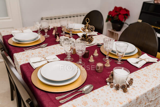 Dall'alto di tavola apparecchiando con occhiali e posate vicino a piatti decorati con candele e coni per celebrazione di Natale — Foto stock