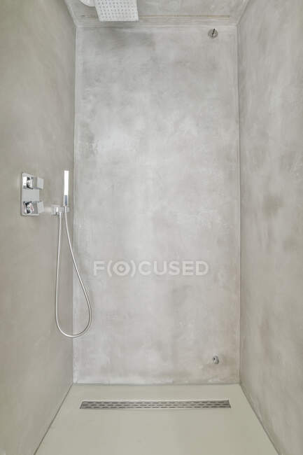 Cabina de ducha limpia vacía con paredes de hormigón gris en baño moderno en apartamento - foto de stock