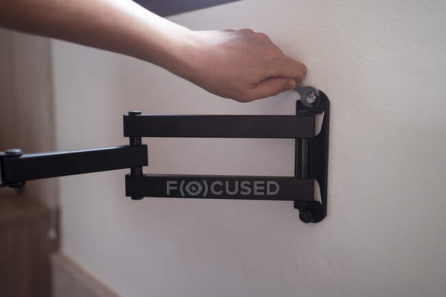 Crop persona irriconoscibile con chiave staffa di fissaggio su parete bianca durante il processo di ristrutturazione in casa — Foto stock