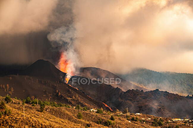 Lava caliente y magma saliendo del cráter cerca de las casas de la ciudad. Cumbre Vieja erupción volcánica en La Palma Islas Canarias, España, 2021 - foto de stock