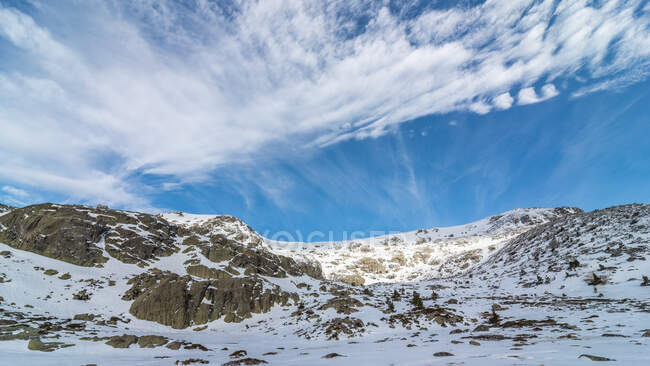 Paysage pittoresque de montagnes rocheuses rugueuses couvertes de neige située à la campagne sous un ciel bleu nuageux en plein jour — Photo de stock