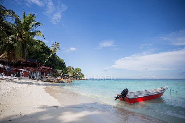 Човен на чистому блакитному морі, що котиться на мокрому піщаному пляжі в Малайзії. — стокове фото