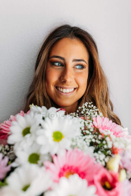 Portrait of gorgeous teen girl at home holding beautiful flowers and looking away — Stock Photo