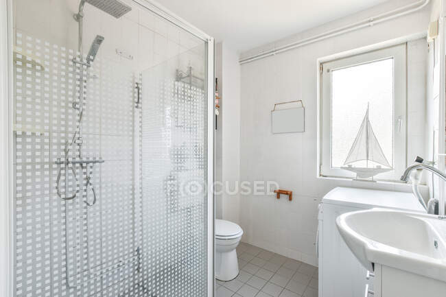 Душова кабіна і туалет в білій плитці ванна кімната, спроектована в мінімальному стилі в сучасній квартирі — стокове фото