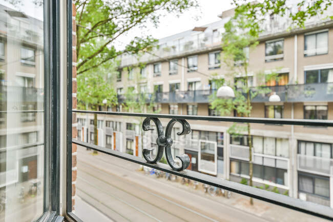 Міський балкон з декором на паркані проти сучасного житлового будівництва екстер'єру та дерев вдень — стокове фото